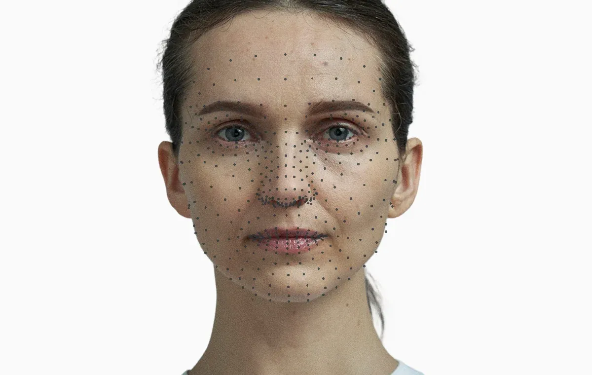 A frontal portrait with several hundred small landmark points mapped across the face, showing the kind of measurement an analysis works from
